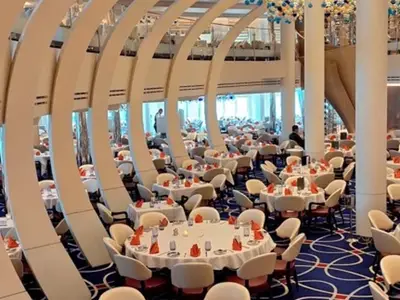 Einblick in das stilvolle Restaurant an Bord der Rotterdam mit modernen weißen Design-Elementen und gedeckten runden Tischen.