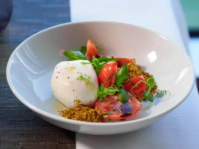 Eine köstliche Burrata mit Tomaten und Basilikum in einer weißen Schale serviert an Bord der Rotterdam.