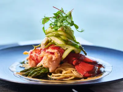 Ein appetitlich angerichtetes Hummergericht mit Spargel und Pasta im Restaurant an Bord der Rotterdam.