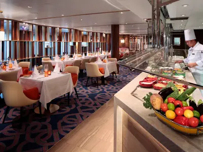 Der exklusive Club Orange Speisebereich an Bord der Rotterdam mit elegant gedeckten Tischen und frischen Speisen am Buffet.