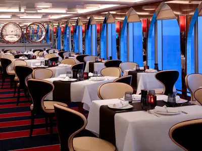 Stilvoll gedeckte Tische im Canaletto Restaurant an Bord der Rotterdam mit Blick durch große Fenster auf das blaue Meer.