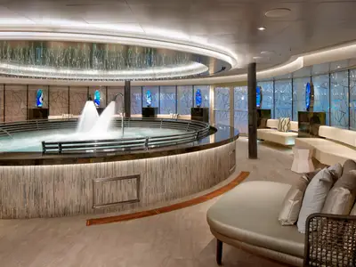 Ein runder Thermal-Pool mit Wasserspielen und bequemen Entspannungsliegen im Greenhouse Spa an Bord der Rotterdam.