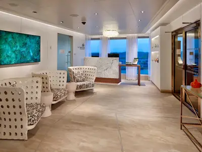 Moderner Empfangsbereich des Greenhouse Spa & Salon an Bord der Rotterdam mit stilvollen Sesseln und Marmortresen.