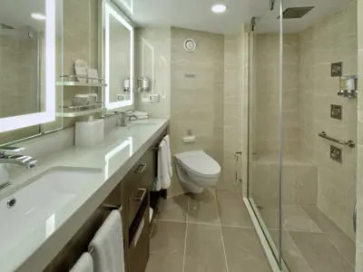 Das luxuriöse Badezimmer einer Suite an Bord der Rotterdam mit Doppelwaschbecken, WC und geräumiger Glasdusche.