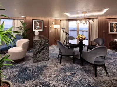 Die luxuriöse Pinnacle Suite an Bord der Rotterdam mit eleganten Sesseln, Esstisch und edler Einrichtung.