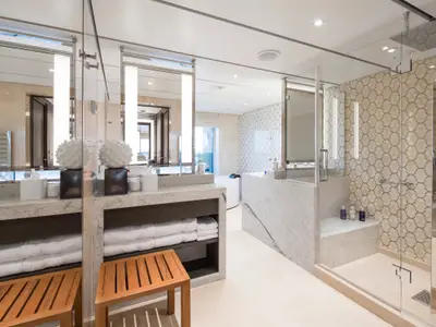 Das großzügige Badezimmer der Pinnacle Suite an Bord der Rotterdam bietet elegante Marmor-Waschtische und eine moderne Glasdusche.