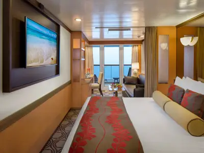 Innenansicht einer gemütlichen Balkonkabine an Bord der Volendam mit großem Bett, TV, Sofa und Balkon.