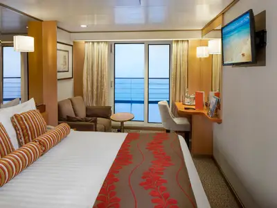 Blick in eine komfortable Balkonkabine an Bord der Volendam mit Doppelbett, Sitzecke und Balkontür zum Meer.