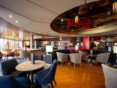 Blick in die stilvoll eingerichtete Ocean Bar an Bord der Volendam mit Sesseln, Holzboden und Deckenverkleidung.