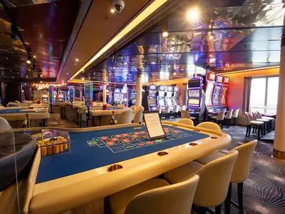 Blick auf den Roulettetisch und moderne Spielautomaten im stilvoll beleuchteten Casino an Bord der Volendam.