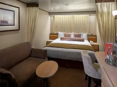 Blick in eine behaglich eingerichtete Innenkabine an Bord der Volendam mit Doppelbett, Sofa und Schreibtisch.
