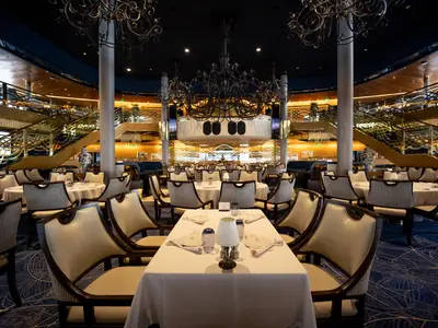 Blick in das elegante zweistöckige Hauptrestaurant an Bord der Volendam mit klassisch gedeckten Tischen und prunkvollen Leuchtern.