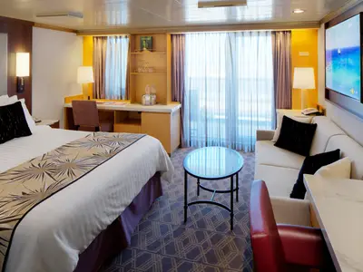 Blick in eine geräumige Balkonkabine an Bord der Westerdam mit großem Doppelbett, Sofa und Couchtisch.