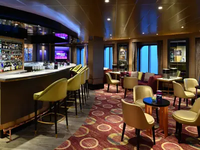 Die stilvoll eingerichtete Billboard Onboard Lounge an Bord der Westerdam mit gelben Barhockern und Sesseln.