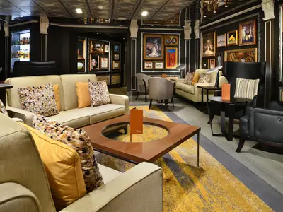 Innenansicht der stilvollen Gallery Bar an Bord der Westerdam mit Sesseln, Sofas und zahlreichen Kunstwerken an den Wänden.