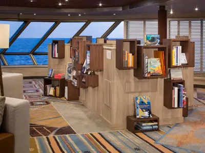 Das gemütliche Explorations Café mit modern gestalteten Bücherregalen und Meerblick an Bord der Westerdam.