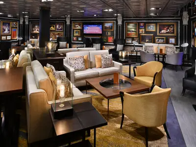 Blick in die stilvoll eingerichtete Gallery Bar an Bord der Westerdam mit gemütlichen Sitzecken und zahlreichen Gemälden.