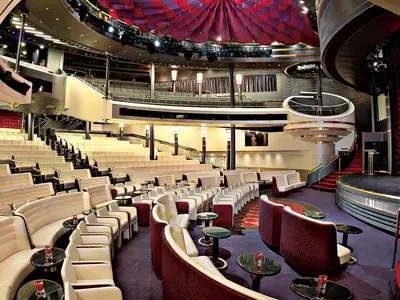 Blick in das leere, stilvolle Theater namens Vista Lounge an Bord der Westerdam mit roten Vorhängen und gemütlichen Sitzen.
