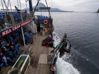Passagiere der Westerdam auf einem Ausflugsboot in Alaska, während ein Guide an Deck die Fischer-Ausrüstung erklärt.