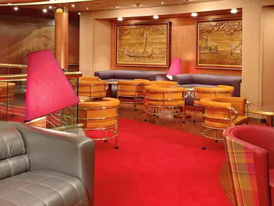 Elegante Lounge an Bord der Westerdam mit orangefarbenen Sesseln, rotem Teppich, roten Lampen und maritimen Wandbildern.