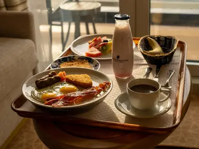 Frühstückstablett an Bord der Westerdam mit Eiern, Speck, Toast, Kaffee und frischem Obst bei warmem Sonnenlicht.