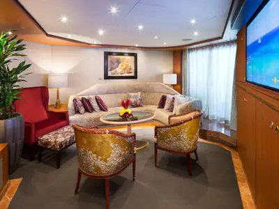 Blick in eine elegante Suite an Bord der Westerdam mit Sofa, Sesseln im Pfauen-Design und Fernseher.