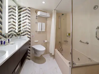 Das moderne Badezimmer einer Suite an Bord der Westerdam verfügt über eine Badewanne, Toilette und ein stilvolles Doppelwaschbecken.