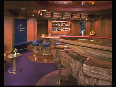 Blick in die klassisch eingerichtete Piano Bar mit einem hölzernen Flügel und Barhockern an Bord der Zaandam.