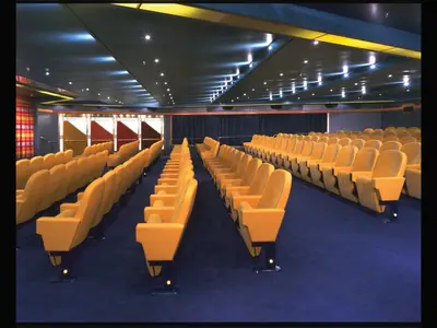 Blick in das Wajang Theater an Bord der Zaandam mit gelben Kinosesseln und blauem Teppichboden.