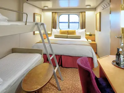 Außenkabine an Bord der Zuiderdam mit einem Doppelbett, einem Etagenbett, einem Schreibtisch und Meerblick.
