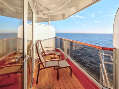 Der private Balkon einer Kabine an Bord der Zuiderdam mit zwei Sesseln und Blick auf das ruhige blaue Meer.