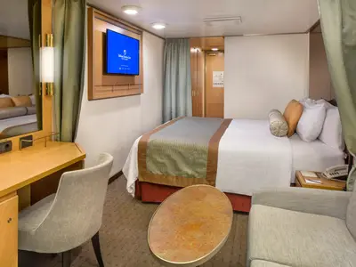 Einblick in eine stilvolle Balkonkabine an Bord der Zuiderdam mit gemütlichem Doppelbett, Schreibtisch und Sofa.