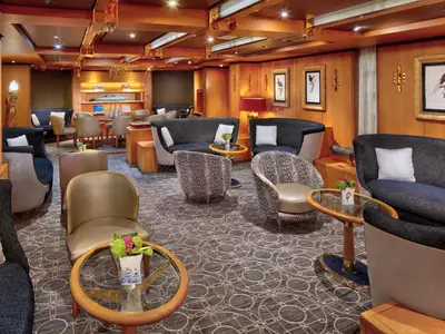Die stilvolle Neptune Lounge an Bord der Zuiderdam bietet gemütliche Sessel, kleine Tische und elegante Holztäfelung für gehobenen Komfort.
