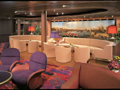 Stilvoller Loungebereich an Bord der Zuiderdam mit beigen und lila Sesseln vor einem großen Venedig-Gemälde.