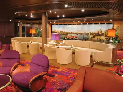 Die Explorer's Lounge an Bord der Zuiderdam bietet bequeme Sessel und Sofas vor einem großen Gemälde von Venedig.