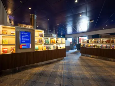 Einblick in die moderne, beleuchtete Bibliothek an Bord der Zuiderdam mit gemütlichen Sitzecken und vollen Bücherregalen.