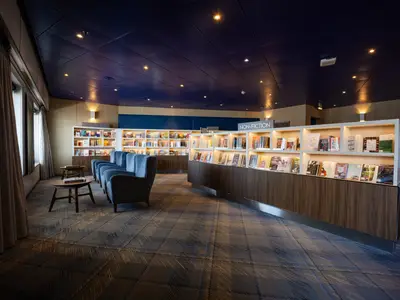Die gemütliche Bibliothek an Bord der Zuiderdam mit bequemen blauen Sesseln, Holztischen und gut sortierten Bücherregalen lädt zum Verweilen ein.