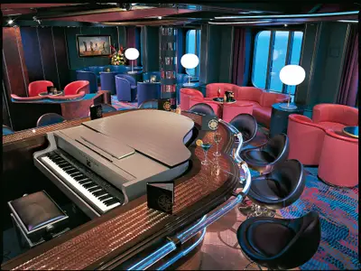 Die Piano Bar an Bord der Zuiderdam mit einem silberfarbenen Flügel-Tresen, umringt von Barhockern und bunten Sesseln.