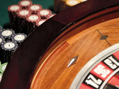 Nahaufnahme eines hölzernen Roulette-Rads und gestapelter Jetons im eleganten Casino an Bord der Zuiderdam.