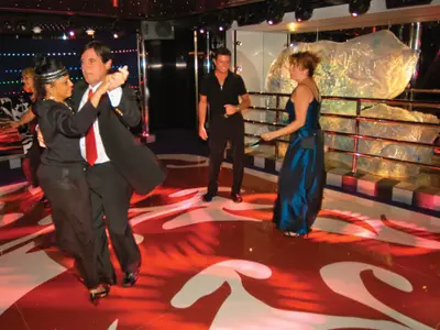 Gäste tanzen auf der bunt beleuchteten Tanzfläche im Northern Lights Nachtclub an Bord der Zuiderdam.