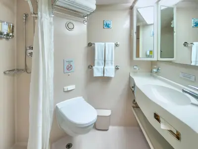 Blick in das kompakte, helle Badezimmer einer Kabine an Bord der Zuiderdam mit Waschbecken, Toilette und Dusche.