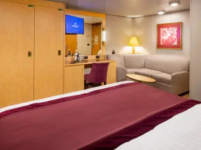 Innenansicht einer geräumigen Innenkabine an Bord der Zuiderdam mit Bett, Sofa, Sessel und Schreibtisch.