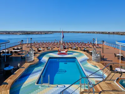 Blick auf den einladenden Sea View Pool und das Sonnendeck an Bord der Zuiderdam bei klarem, blauem Himmel.