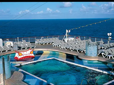 Blick auf den Sea View Pool an Bord der Zuiderdam mit blauen Liegestühlen vor dem weiten blauen Ozean.