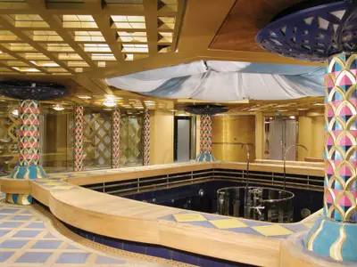 Blick auf den farbenfrohen Hydrotherapie-Pool an Bord der Zuiderdam mit verzierten Säulen, Holzumrandung und Mosaikdetails im Wellnessbereich.