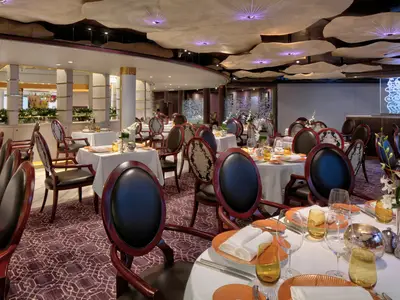 Das stilvoll gedeckte Pinnacle Grill Restaurant an Bord der Zuiderdam mit runden Lederstühlen und kunstvoller Deckenbeleuchtung.