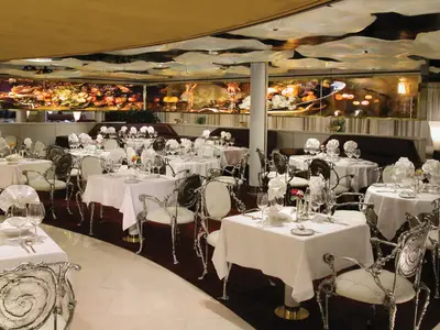 Der elegant eingedeckte Pinnacle Grill an Bord der Zuiderdam mit weißen Tischdecken und verzierten Silberstühlen.