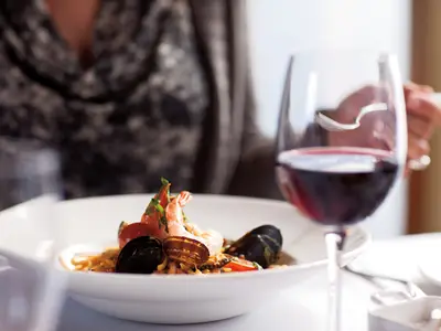 Ein Teller mit frischen Meeresfrüchten und ein Glas Rotwein beim Abendessen im Pinnacle Grill an Bord der Zuiderdam.