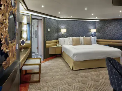 Ein Blick in die luxuriös gestaltete Pinnacle Suite an Bord der Zuiderdam mit Doppelbett, Schminkbereich und Badezimmer-Eingang.