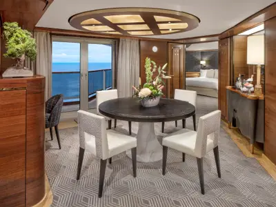 Der elegante Essbereich der Pinnacle Suite an Bord der Zuiderdam mit rundem Tisch, weißen Stühlen und Blick auf den Ozean.
